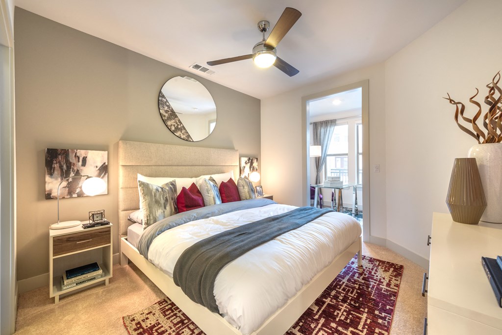 Bedroom with wood flooring and a bed facing the entry doorway into the apartment.