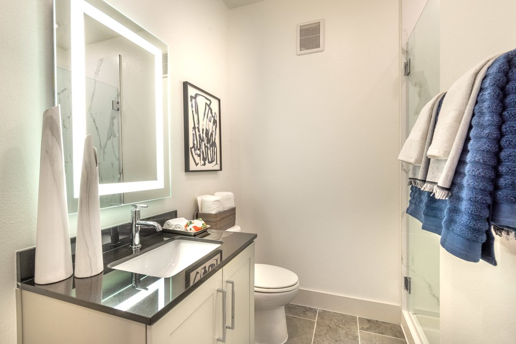 Bathroom facing sink with white cabinets, quartz countertops, and nickel brushed hardware.