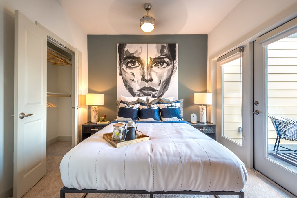 Bedroom facing a bed with two nightstands on the sides facing an exterior patio door