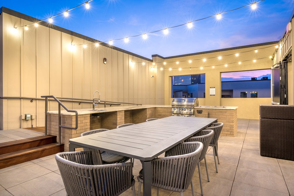 Outdoor grilling area with a long table, sink, and grill facing downtown Dallas