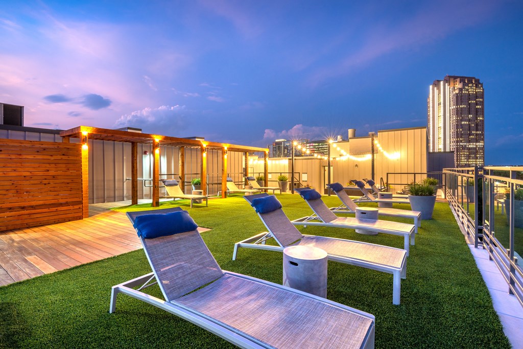 Lounge chairs sitting next to the rooftop pool that faces downtown Dallas