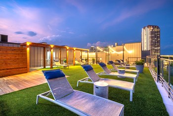 Lounge chairs sitting next to the rooftop pool that faces downtown Dallas - Photo Gallery 6