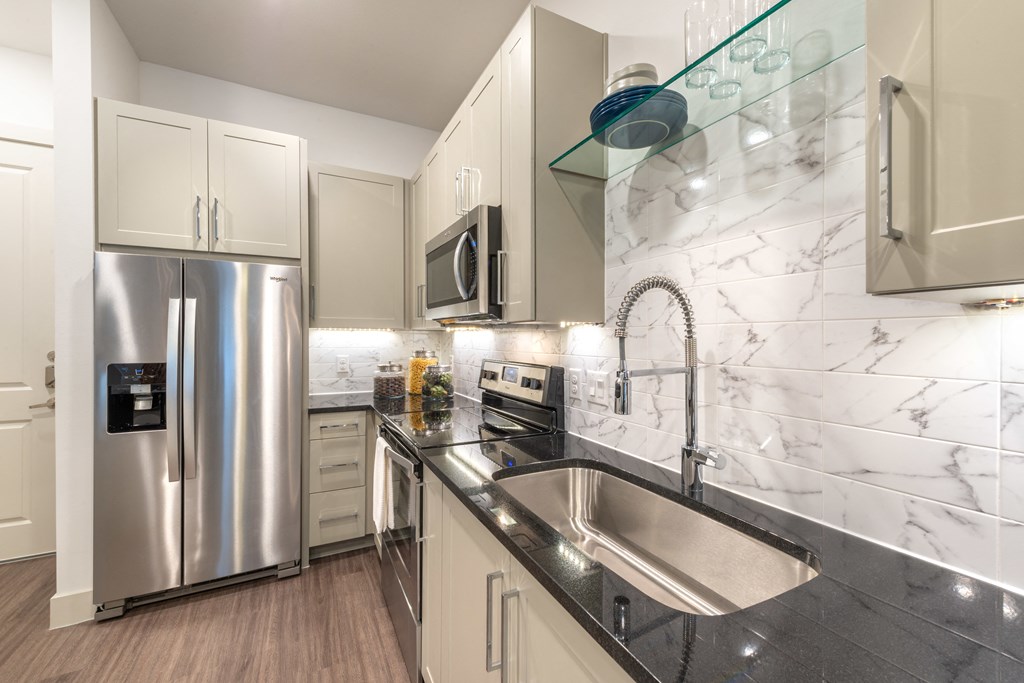 Kitchen with white cabinets, black quartz counter tops and a brushed-nickel gooseneck faucet.