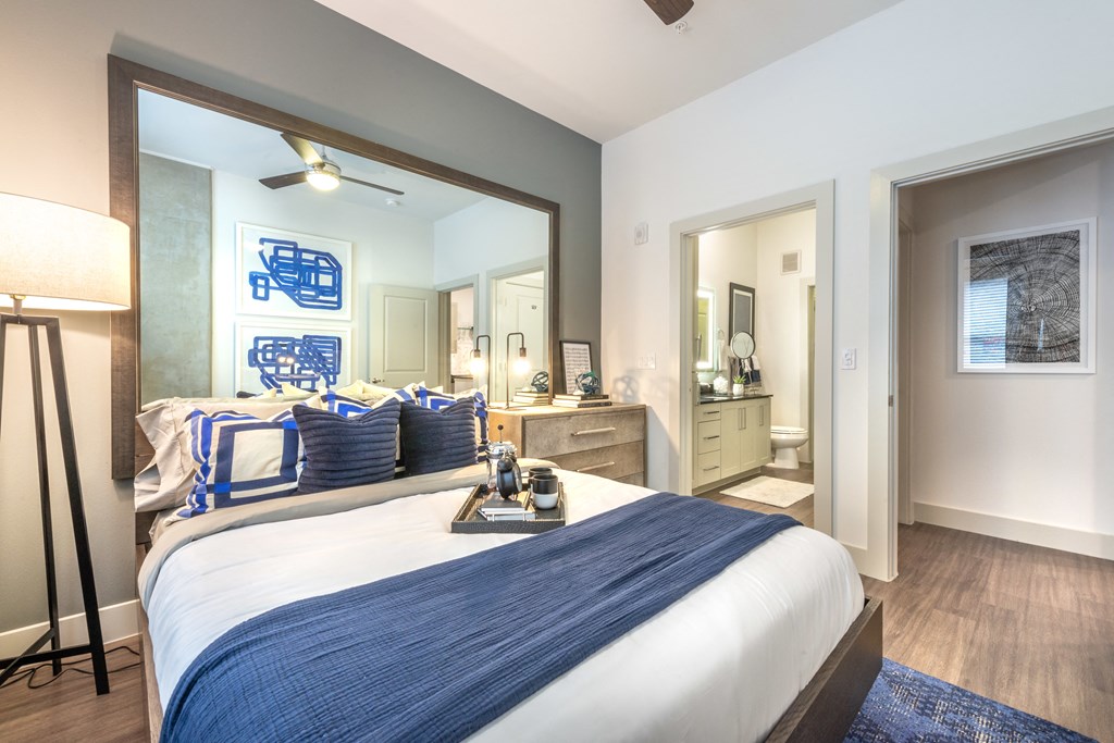 Interior of bedroom facing the bed on all hardwood-style flooring.