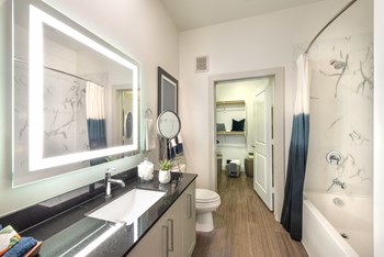 Bathroom area facing sink, back-lit mirror, and bathtub. - Photo Gallery 70