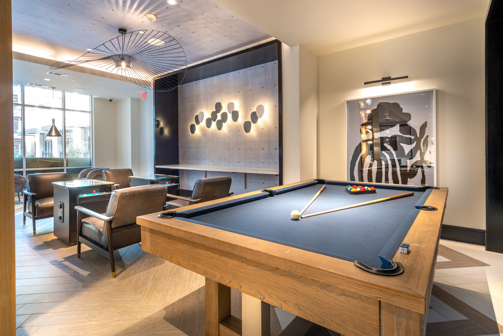 Clubhouse game room with pool table, arcades, unique haning ceiling art and lighted accent wall and countertop