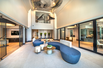 Clubhouse interior with uniquely shaped blue couches, gold table tops, white stools, and and large hanging fixtures - Photo Gallery 17