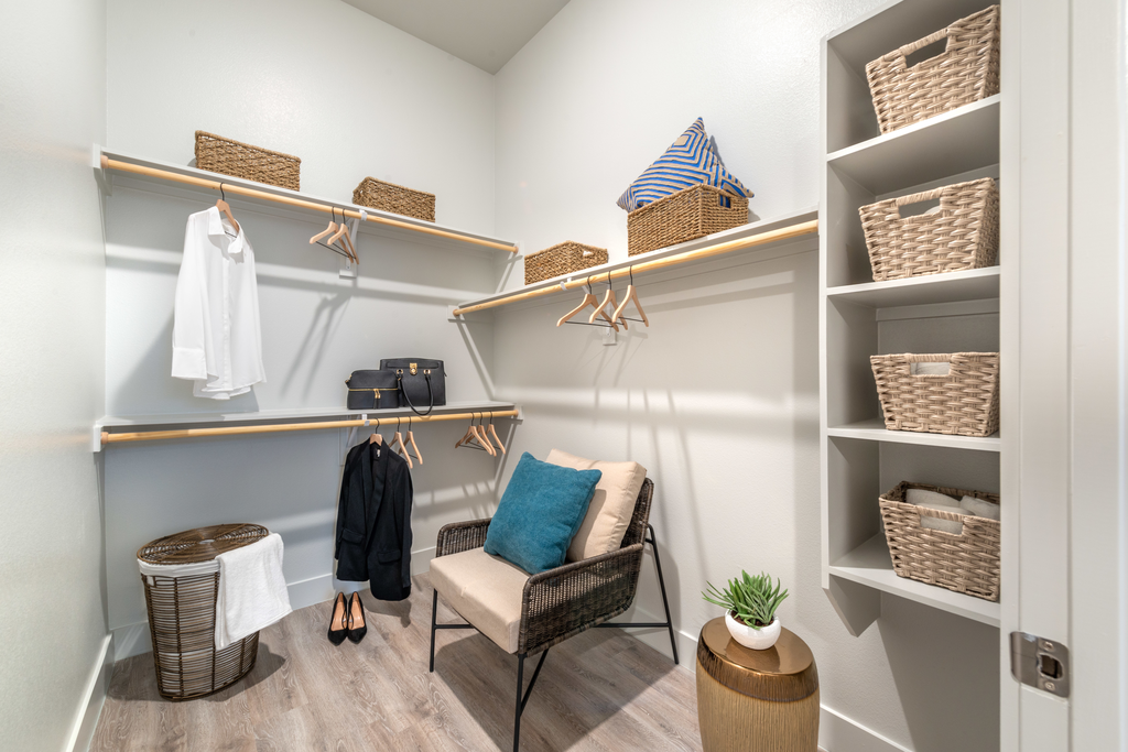 Staged walk in closet with wood style flooring and custom shelving