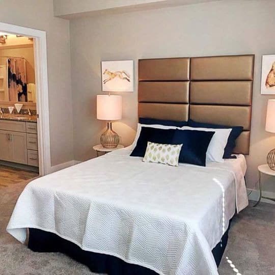 A bed with a white comforter and a blue pillow is in the image at Foxwood Apartments, North Carolina, 27616