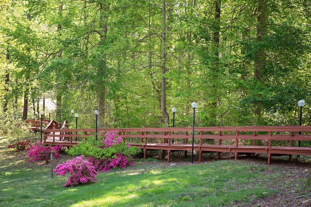 A wooden bench is surrounded by trees and flowers.