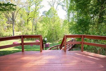 A wooden deck with railings overlooks a lush green forest.