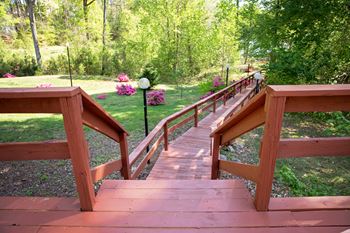A wooden staircase with railings leads up to a lush green area.