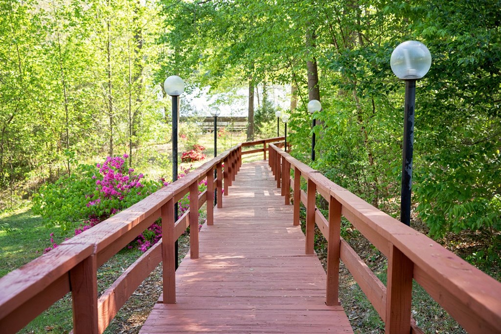 A wooden bridge with railings and lamp posts on either side.