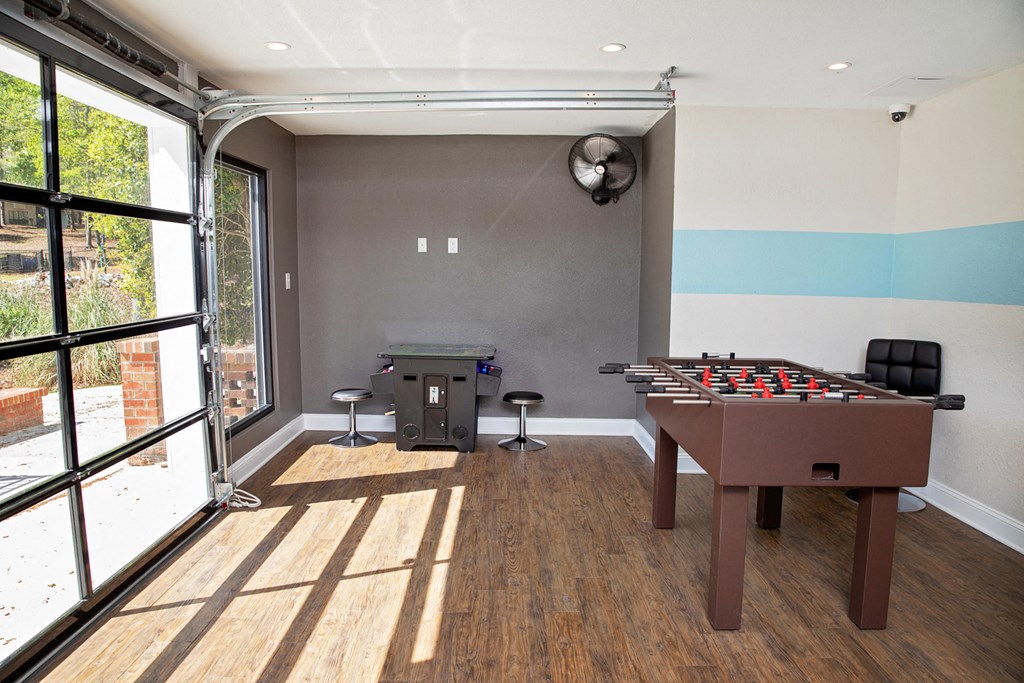 A room with a foosball table and a bar stool.