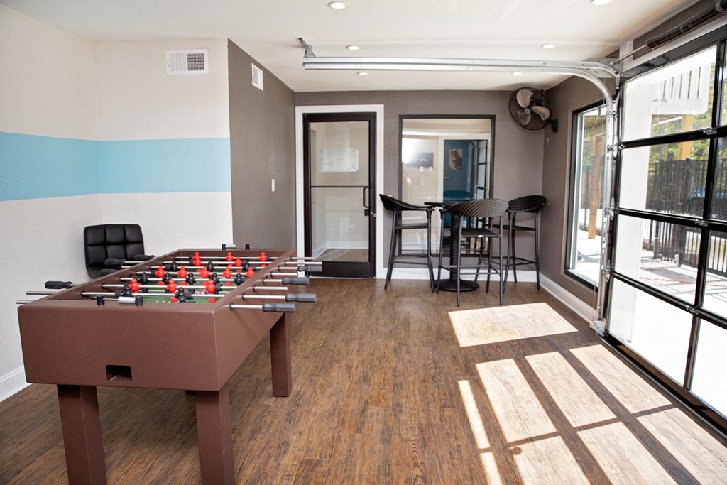 A foosball table in the middle of a room with a sliding glass door.