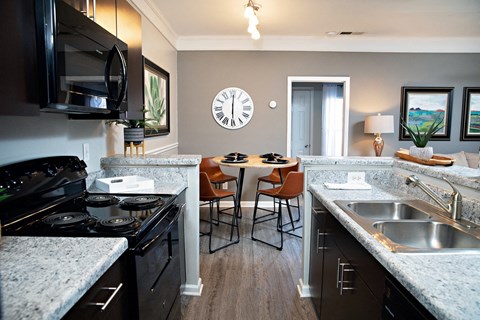 A kitchen with a black stove top oven and a black microwave above it.