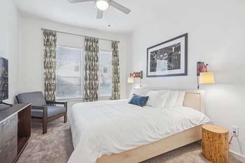 A bedroom with a bed, chair, and a ceiling fan.