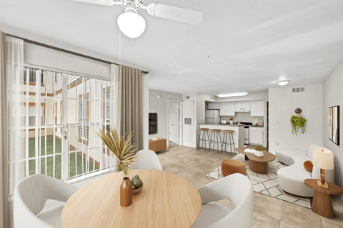 a living room with a large window and a kitchen in the background