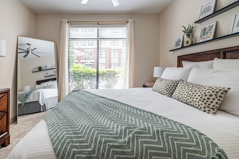 A bedroom with a large bed and a window overlooking a garden.