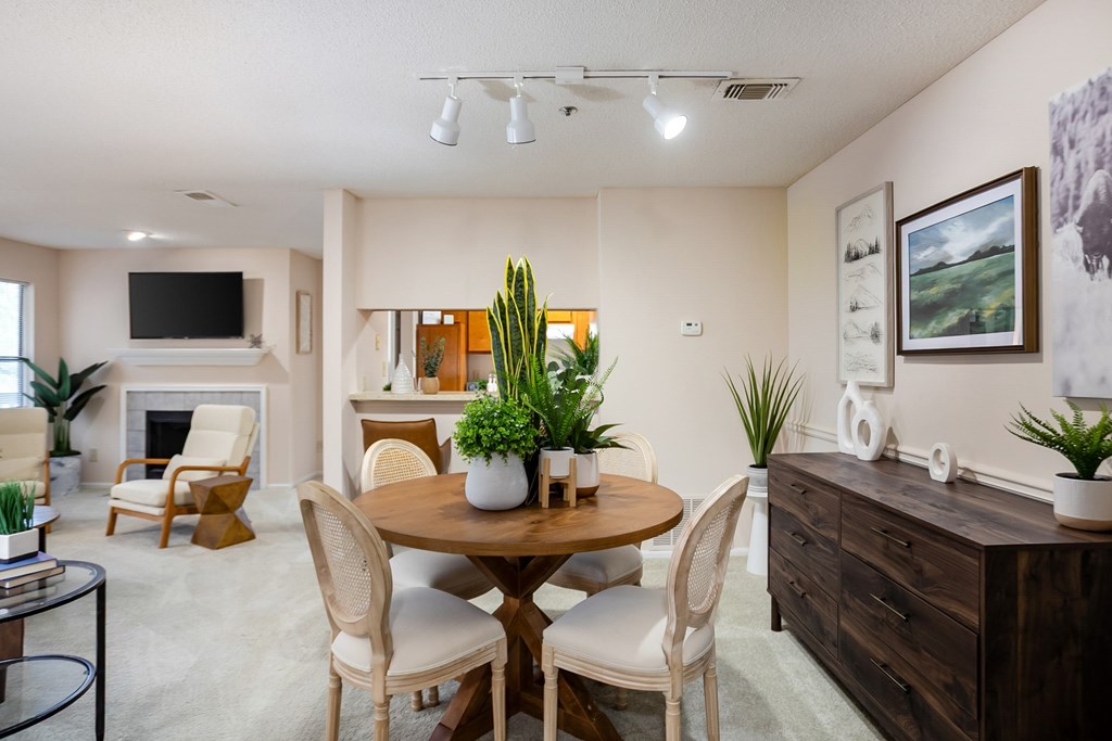 A well-lit living room with a fireplace, chairs, and a dining table.