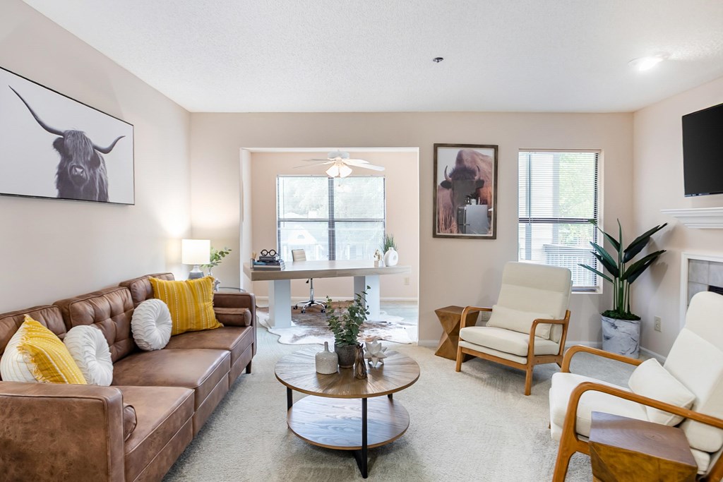 A living room with a brown leather couch, a white armchair, and a coffee table.