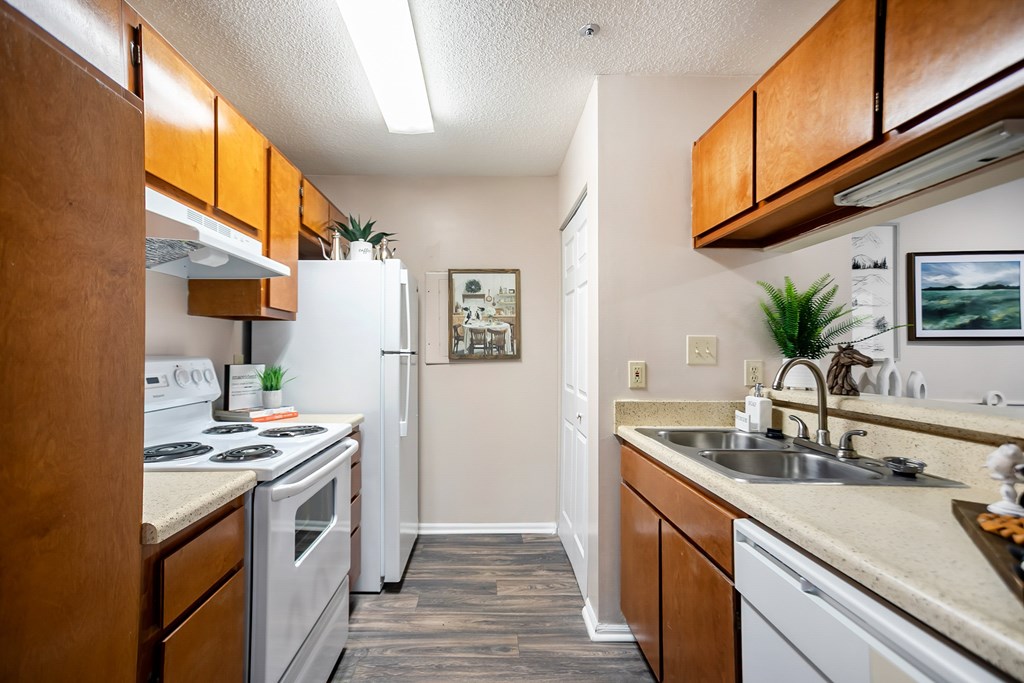 A kitchen with white appliances and wooden cabinets.