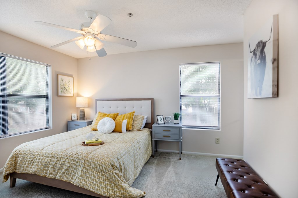 A bedroom with a bed, a bench, and a ceiling fan.