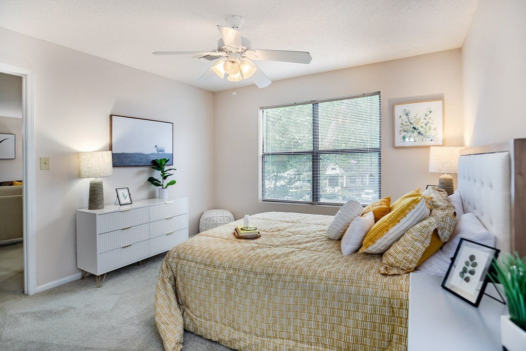 A bedroom with a bed, dresser, and window.
