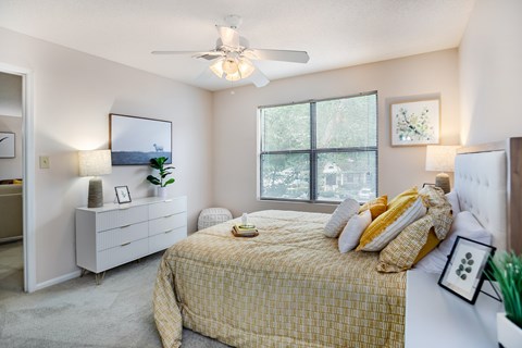 A bedroom with a bed, dresser, and window.
