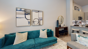 Staged livingroom with blue couch, bar shelf, barstools at kitchen breakfast bar, accent rug and wall art - Photo Gallery 91
