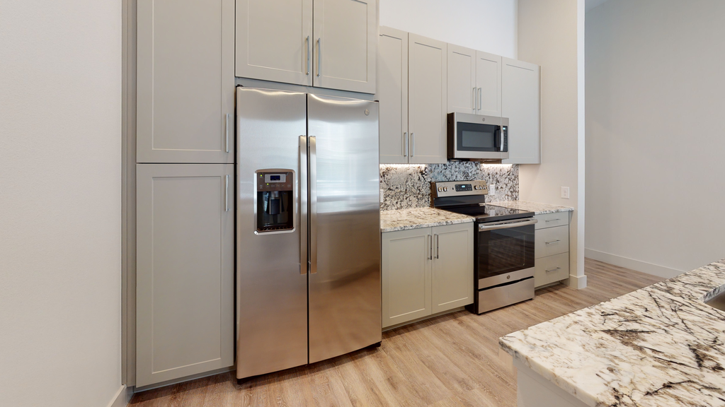 Kitchen with stainless appliances, taupe cabinetry, wood style flooring, granite countertops