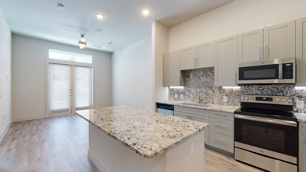 Kitchen with island, granite countertops, taupe cabinetry, stainless appliances, wood style flooring, recessed lights and ceiling fan with light in livingroom