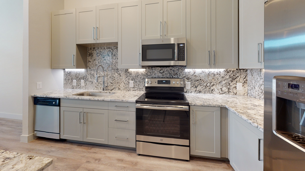 Kitchen with granite countertops, stainless appliances, wood style flooring, shaker cabinetry and goose neck faucet