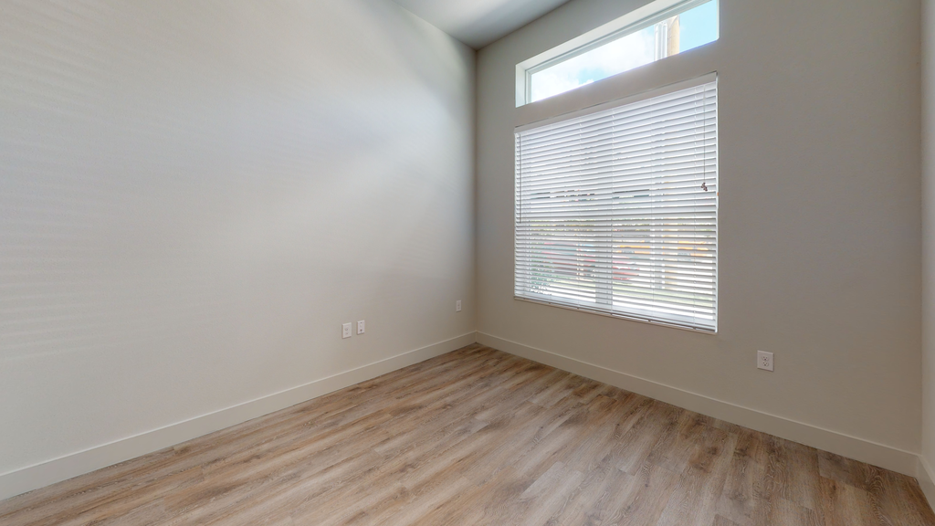 Bedroom with wood style flooring and large window with blinds