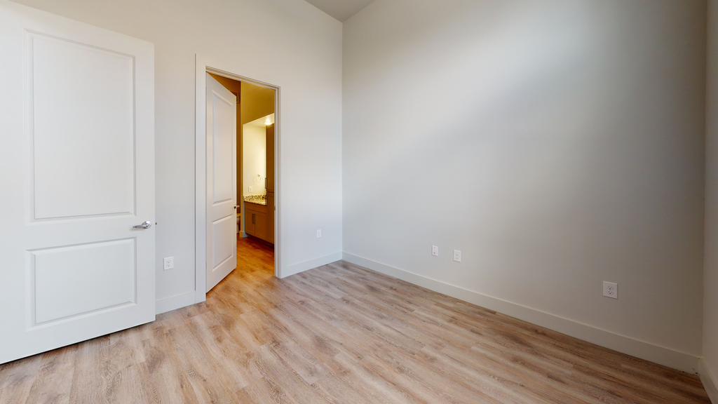 Bedroom with wood style flooring and en-suite bathroom entry