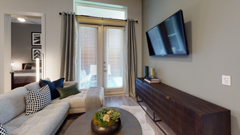 Staged livingroom with couch, accent rug, tv dresser, wall mounted television, patio exit door with blinds and curtains - Photo Gallery 38