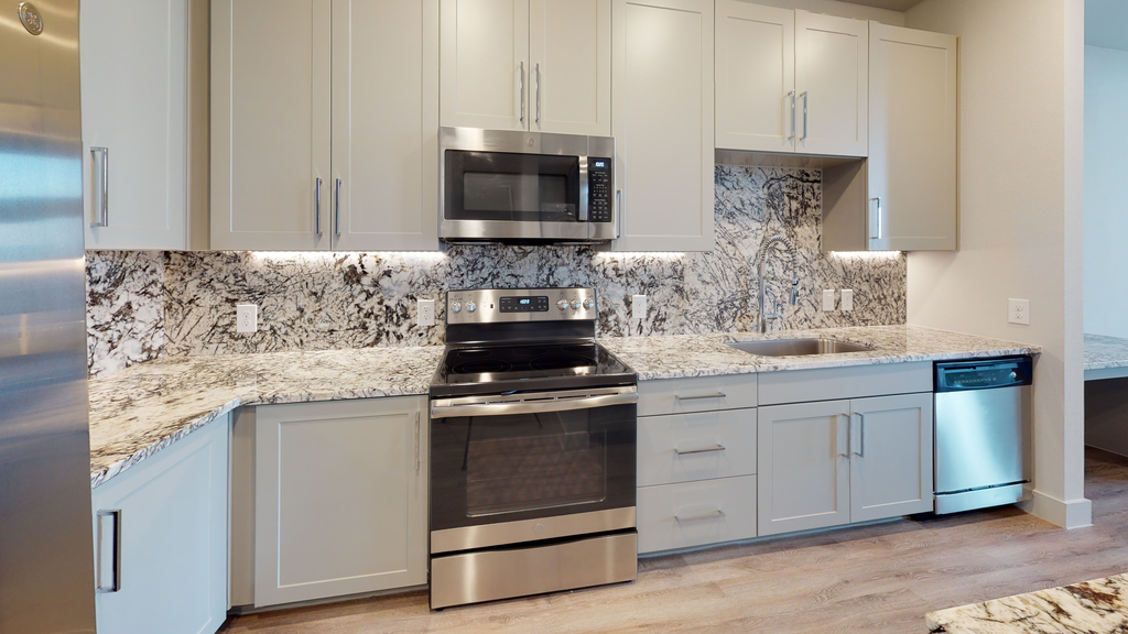 Kitchen with shaker cabinets, stainless appliances, granite countertops and backplash, wood style flooring and undermount gooseneck faucet