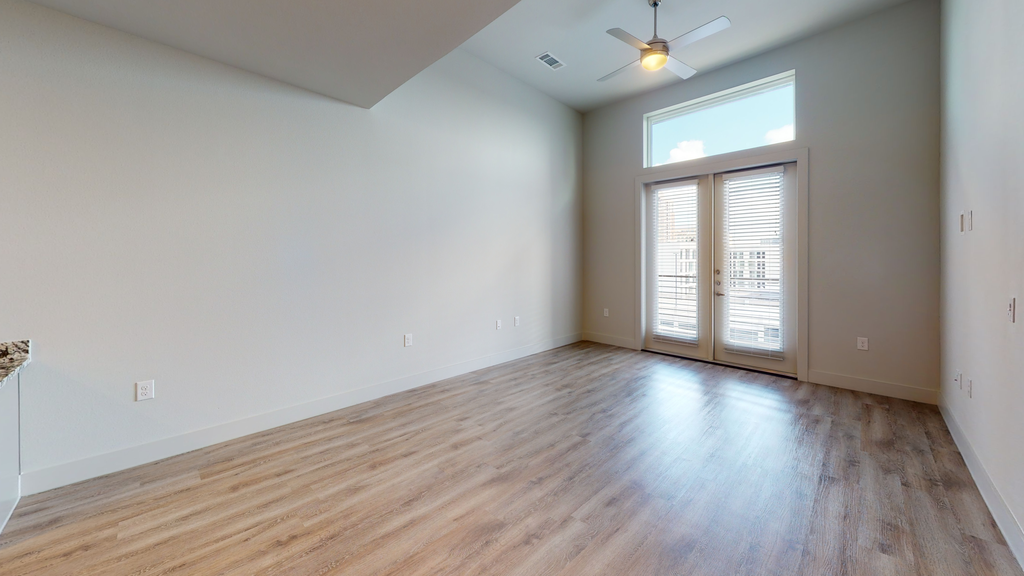 Livingroom with wood style flooring, waulted ceiling, ceiling fan with light and doors with blinds