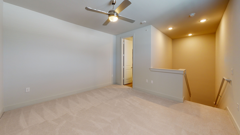 Bedroom at top of stairs with carpet, ceiling fan with light and en-suite bathroom entrance