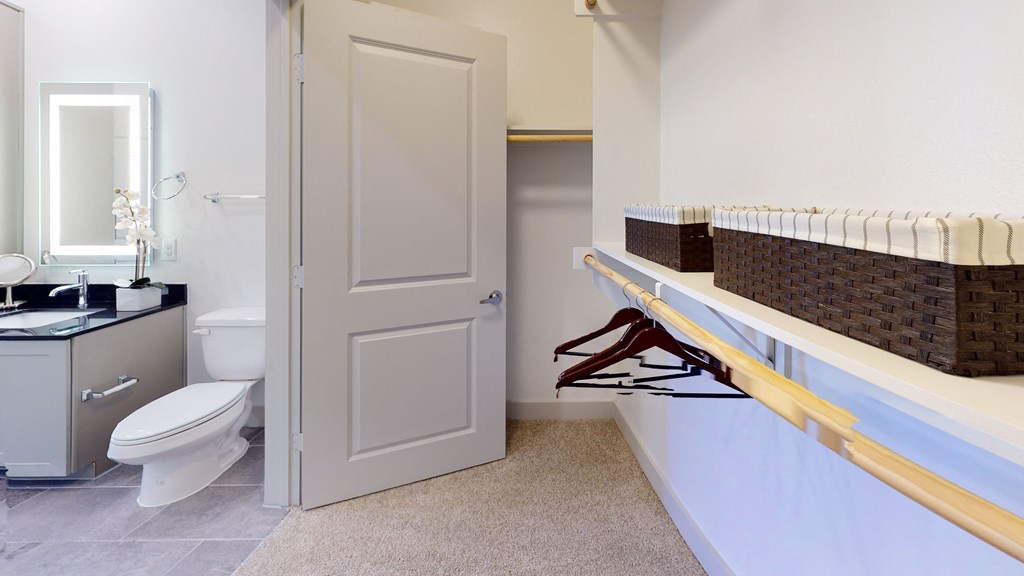 Large walk-in closet facing a long shelf and interior of the bathroom
