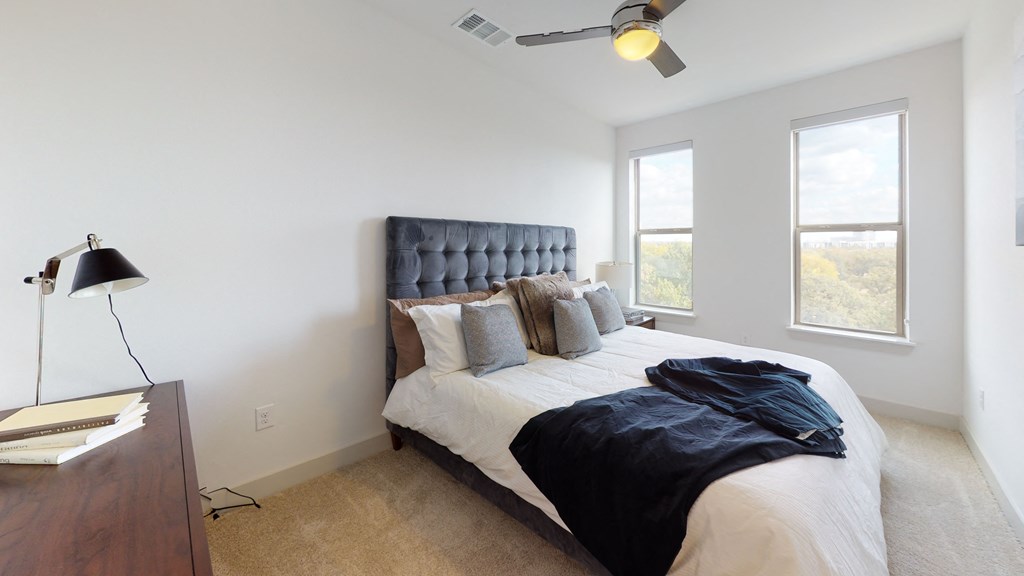 Large bed next to a dresser facing exterior window on carpeted flooring.