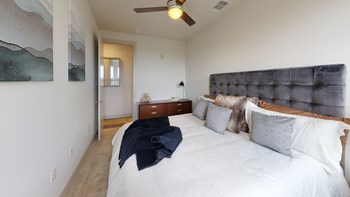 Large bed with a dresser next to it facing the entry door of the bedroom on carpeted flooring. - Photo Gallery 87