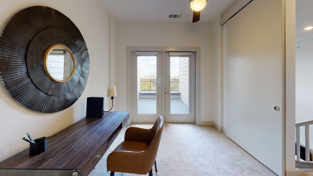Upstairs loft area with a desk and chair facing outdoor patio area.