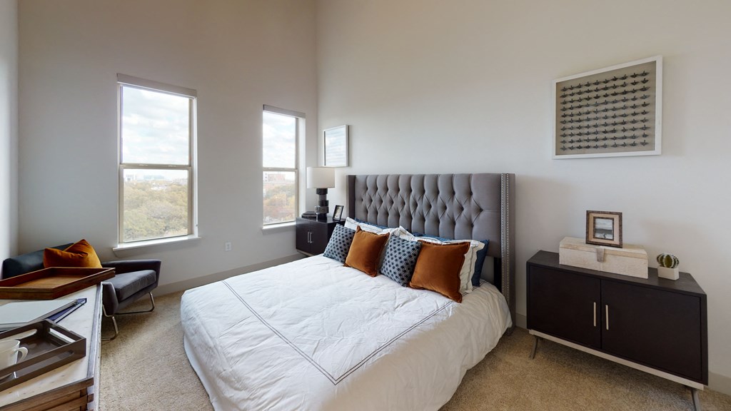 Bed with two nightstands facing an exterior window on carpeted flooring.