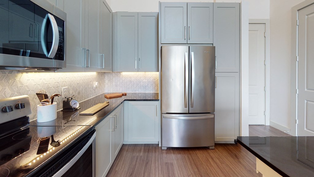 Kitchen with stainless steel appliances, black quartz countertops, and all hardwood style flooring.