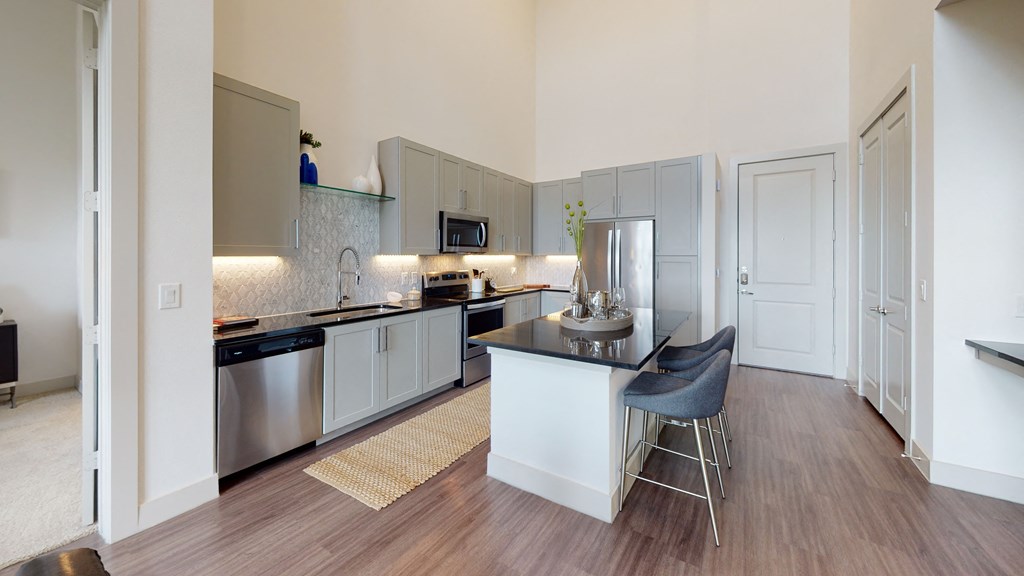 Kitchen facing the entry door, built-in desk, and bar area from the living room.