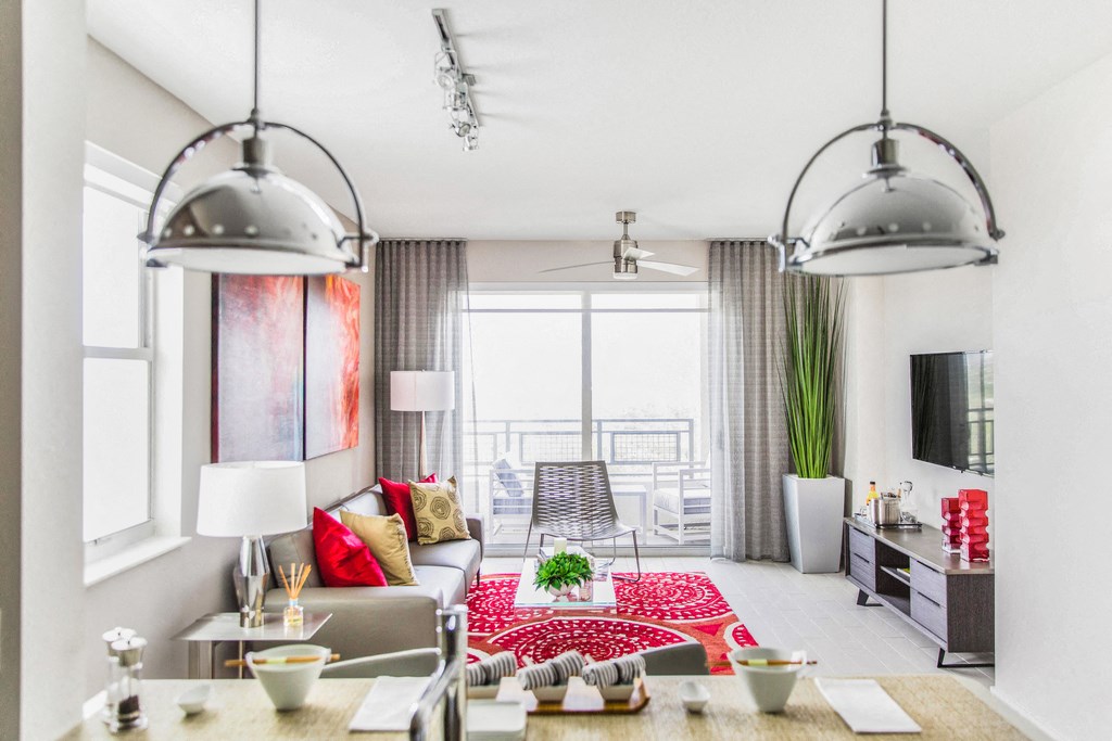 A modern living room with a red rug and a large window.