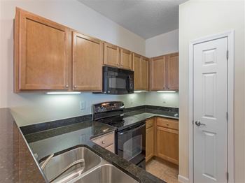 Kitchen with Brown Cabinets Black Appliances and Black Counters Pantry Closet and Breakfast Bar
