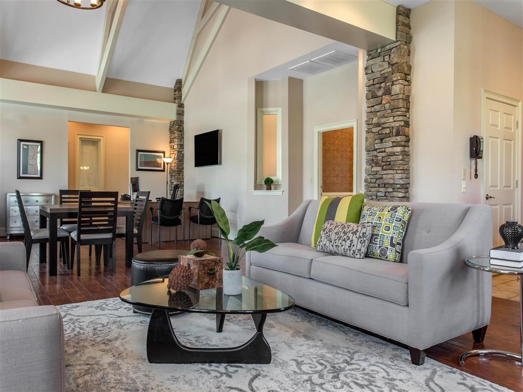 A living room with a grey couch and a glass coffee table.