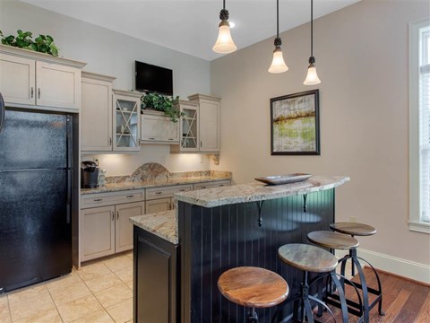 Clubhouse Kitchen with Tan Counters Black Appliances and Wood and Metal Stools at Breakfast Bar